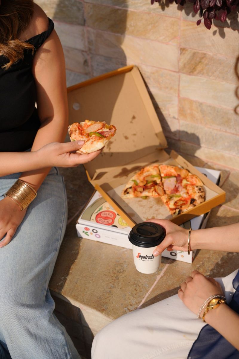 Two women sharing pizza outdoors