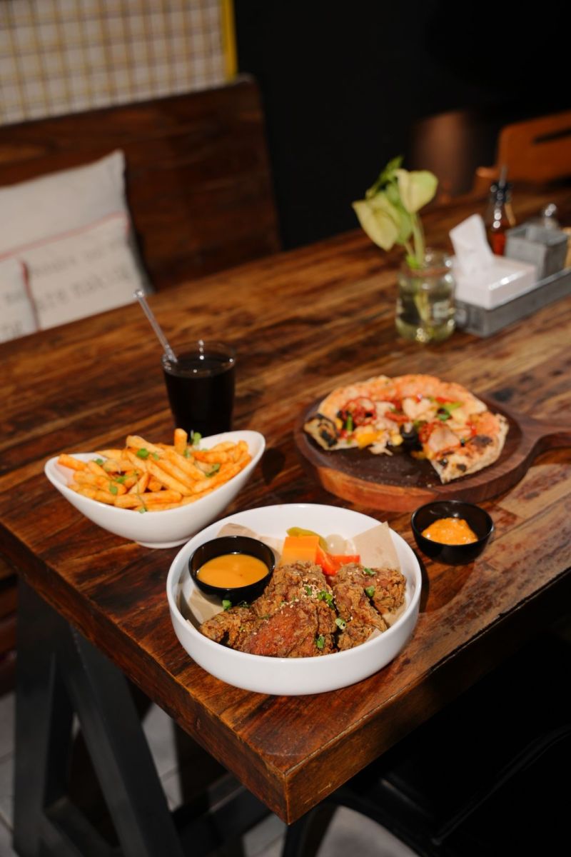 Fried chicken, fries and pizza on a wooden table